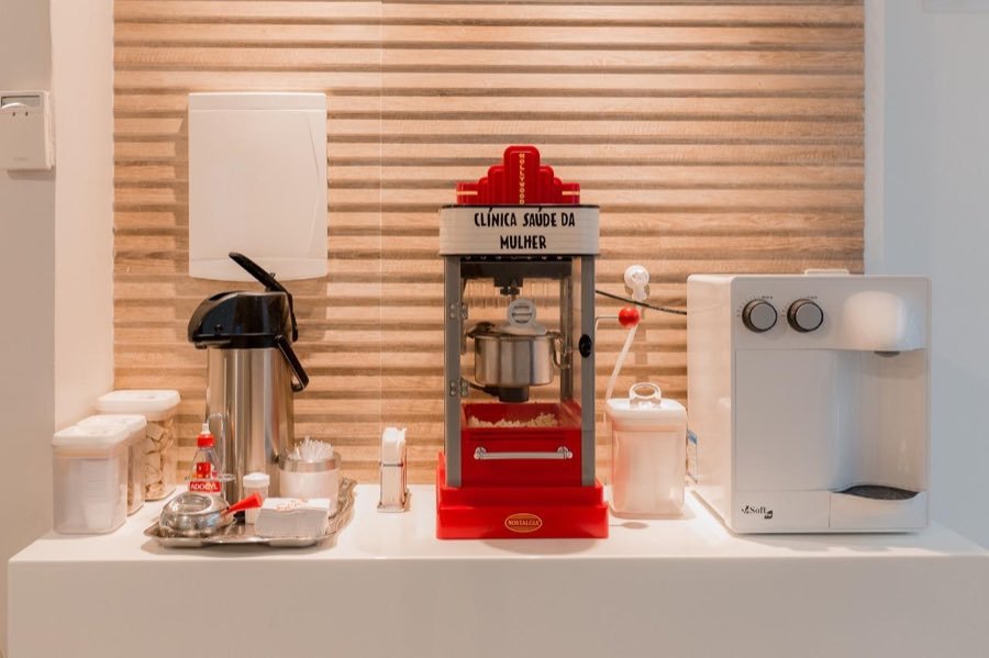 Cantinho do café com garrafa térmica, água e máquina de pipoca