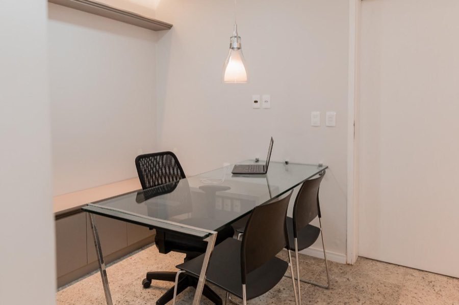 Consultório menor, com mesa de vidro e notebook