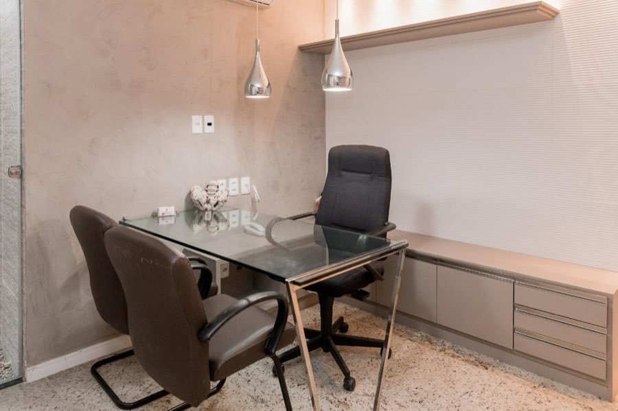Consultório com mesa de vidro e pendentes cromados