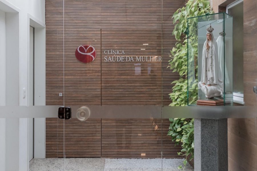 Entrada da clínica com a placa e a imagem de Nossa Senhora em uma vitrine