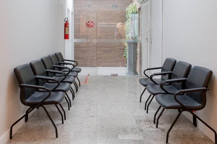 Sala de espera com poltronas e a porta de entrada ao fundo