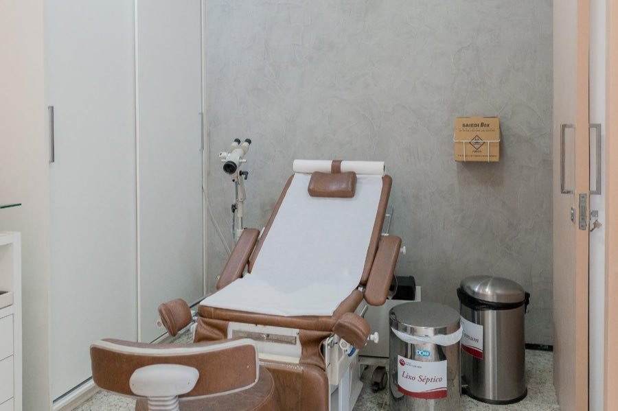 Sala de exame ginecológico com cadeira e colposcópio
